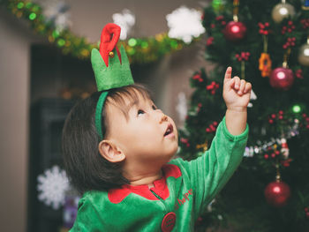 Cute baby girl by christmas tree at home