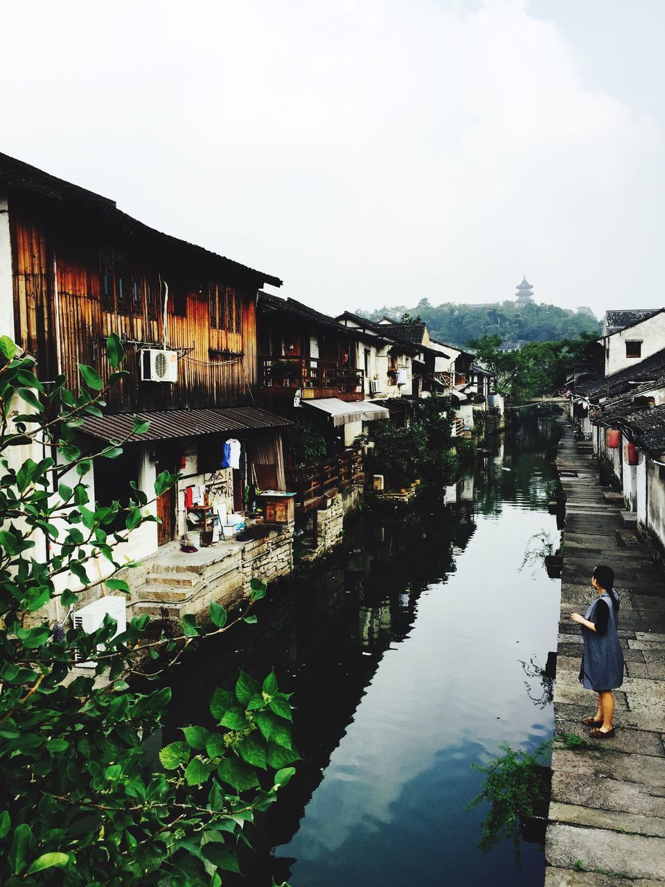 architecture, built structure, building exterior, water, lifestyles, men, leisure activity, person, reflection, walking, house, sky, canal, residential structure, residential building, full length, tree, clear sky