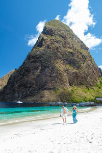 Rear view of woman standing at beach against sky