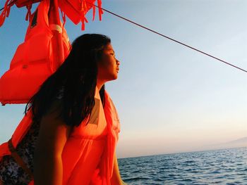 Woman with red umbrella on beach against clear sky