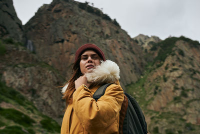 Young woman standing against mountain