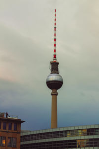 Communications tower in city against sky