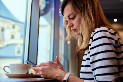 Woman have breakfast at cafe, use smartphone at cafe