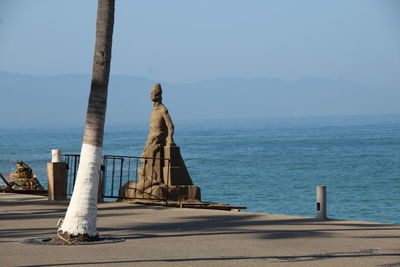 Statue by sea against clear sky