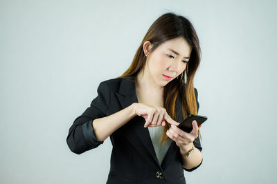 Young woman using mobile phone against white background