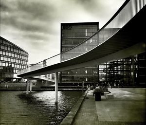 Elevated walkway curving above city square and pond