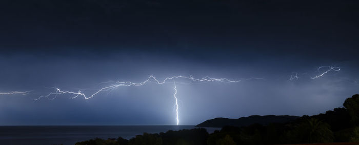 Scenic view of lightning over sea at night