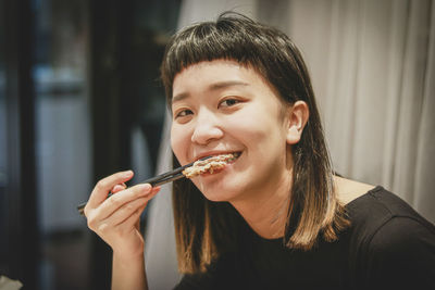 Portrait of woman eating food at home