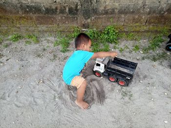 Side view of boy playing with truck toys on road