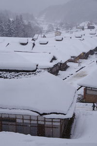 Snow covered field by buildings during winter
