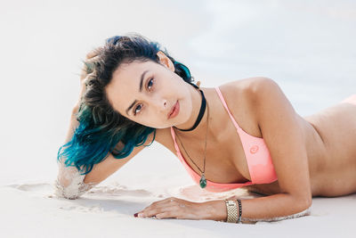 Portrait of smiling young woman at beach against sky