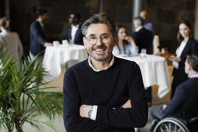 Confident businessman with arms crossed at seminar in conference center