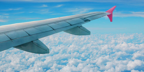 Close-up of airplane wing against cloudy sky