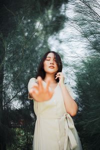 Young woman looking away while standing against trees