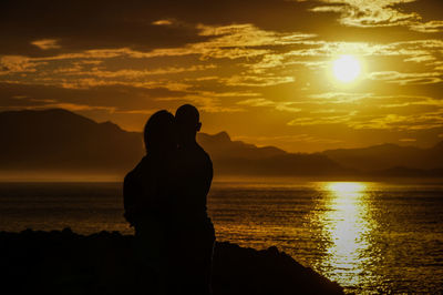 Silhouette couple against sea during sunset