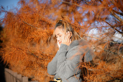 Young woman with autumn leaves against trees