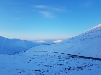 Scenic view of snowcapped mountains against blue sky