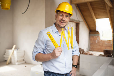 Portrait of smiling man standing against yellow wall