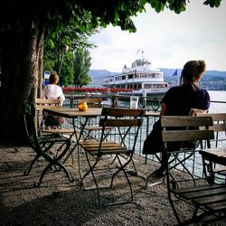 Rear view of woman sitting at cafe by sea