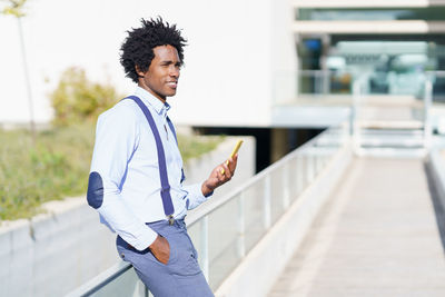 Young man using mobile phone while standing on laptop