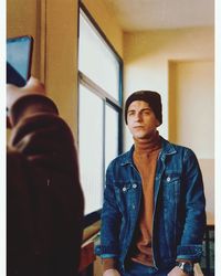 Portrait of young man looking through window