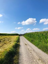 Road amidst field against sky