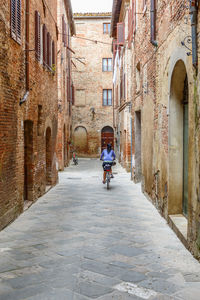 Rear view of man riding bicycle on road in city