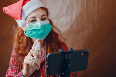 Smiling woman wearing mask cleaning mobile phone