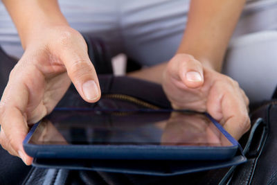 Close-up of woman hand using digital tablet over bag