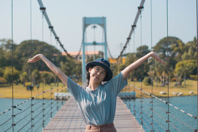 Woman with arms raised standing on footbridge
