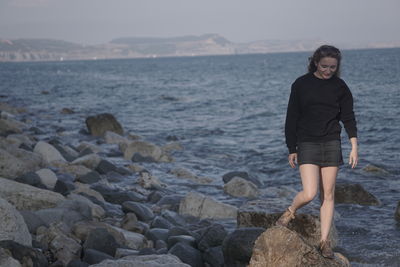 Full length of woman standing on rocky beach