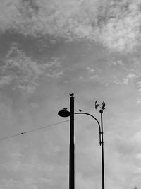 Low angle view of bird on pole against sky