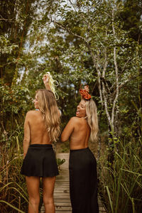 Rear view of woman standing against trees