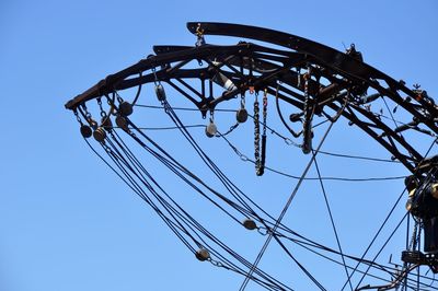 Low angle view of rollercoaster against clear blue sky