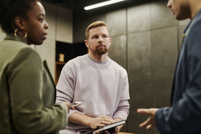 Businessman listening to colleague explaining at office