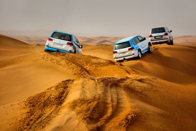 Cars on sand dune in desert