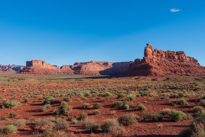 Rock formations on landscape against clear blue sky