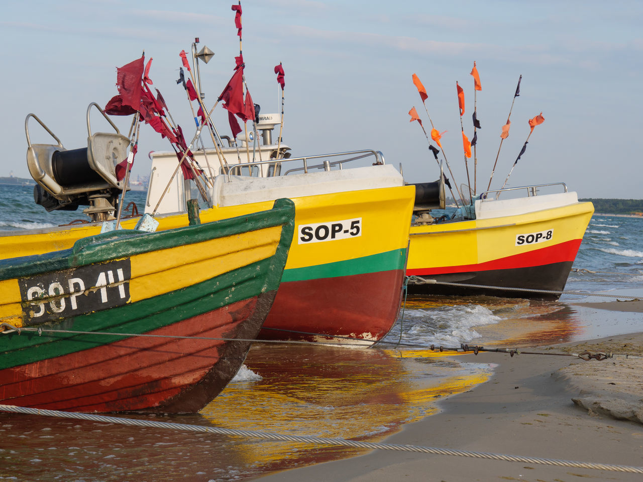 FISHING BOATS MOORED ON BEACH AGAINST SKY