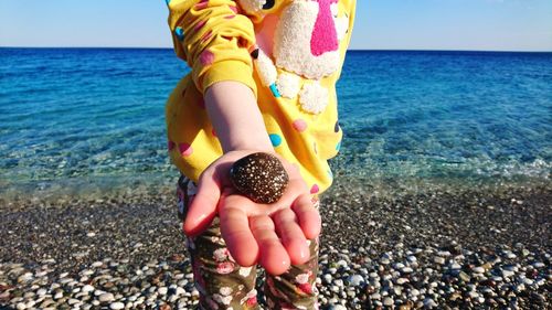Close-up of hand holding sand at beach against clear sky