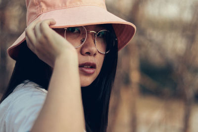 Close-up portrait of young woman wearing hat outdoors