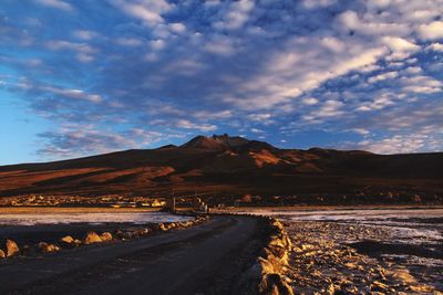 Road leading towards mountains against sky