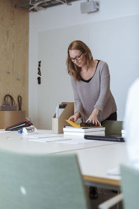 Mid adult female executive examining files on conference table at office