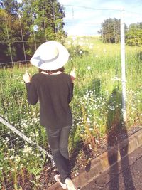 Rear view of woman standing by plants on field