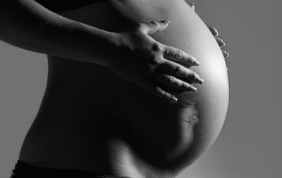 Close-up of woman touching hair over black background