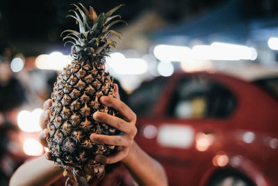 Close-up of hand holding a pineapple at night