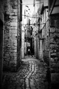 Man walking on alley amidst residential buildings