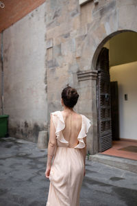 Rear view of woman standing against building