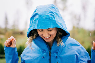 Woman stood in the rain smiling outside in a raincoat