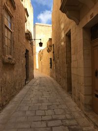 Walkway amidst buildings against sky