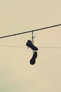 Low angle view of silhouette bird on cable against sky